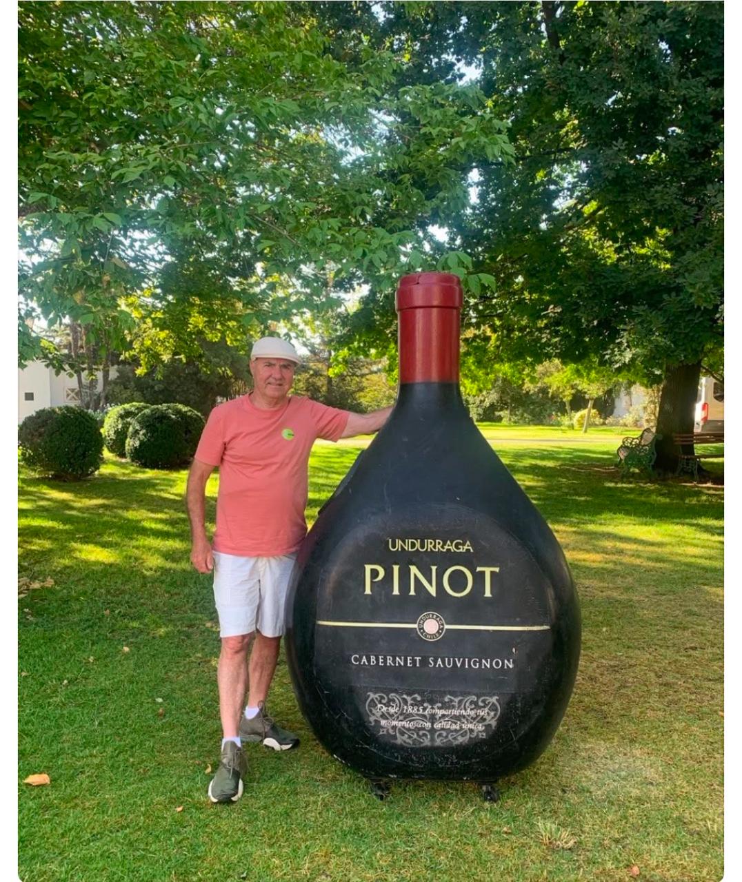 Homem ao lado de uma garrafa cenográfica de vinho em grande escala
