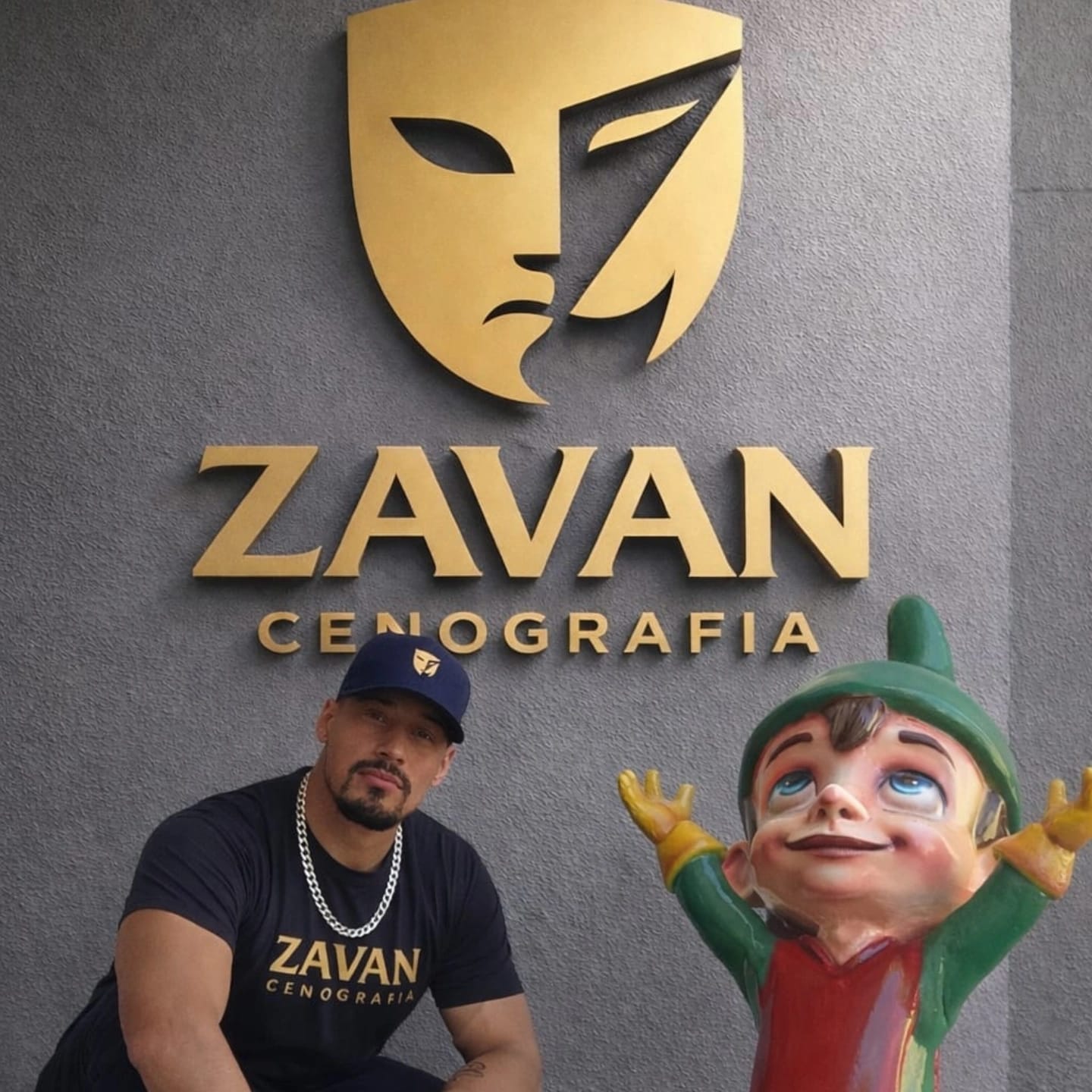 Profissional ao lado de um duende cenográfico diante da marca Zavan